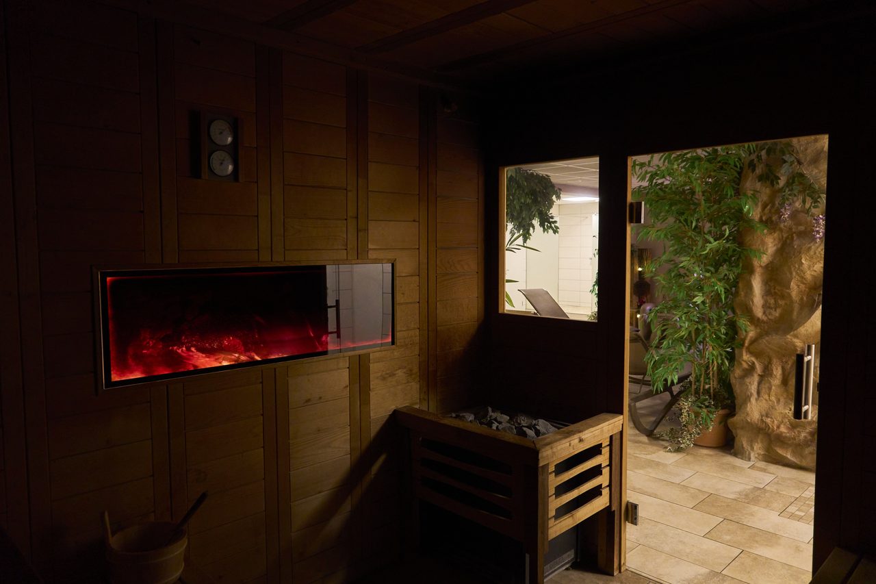 Finnische Sauna mit Saunaofen und beleuchtetem Feuerpaneel